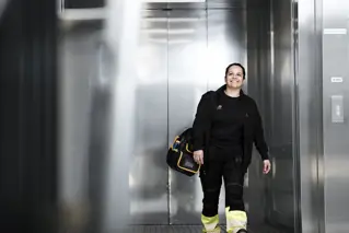 Leende vaktmästare som lämnar hissen.