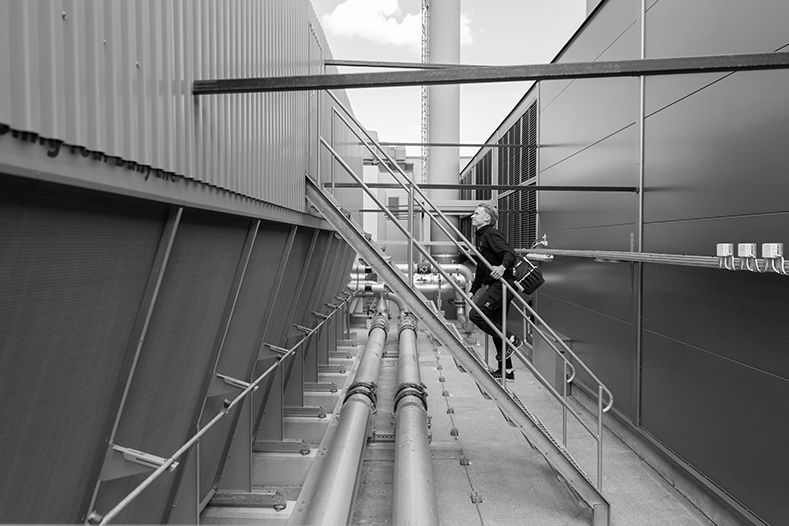 Technical engineer climbing a ladder and holding one hand on the rail