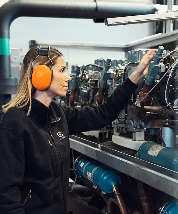 Female property technician with ear protection adjusting a relay