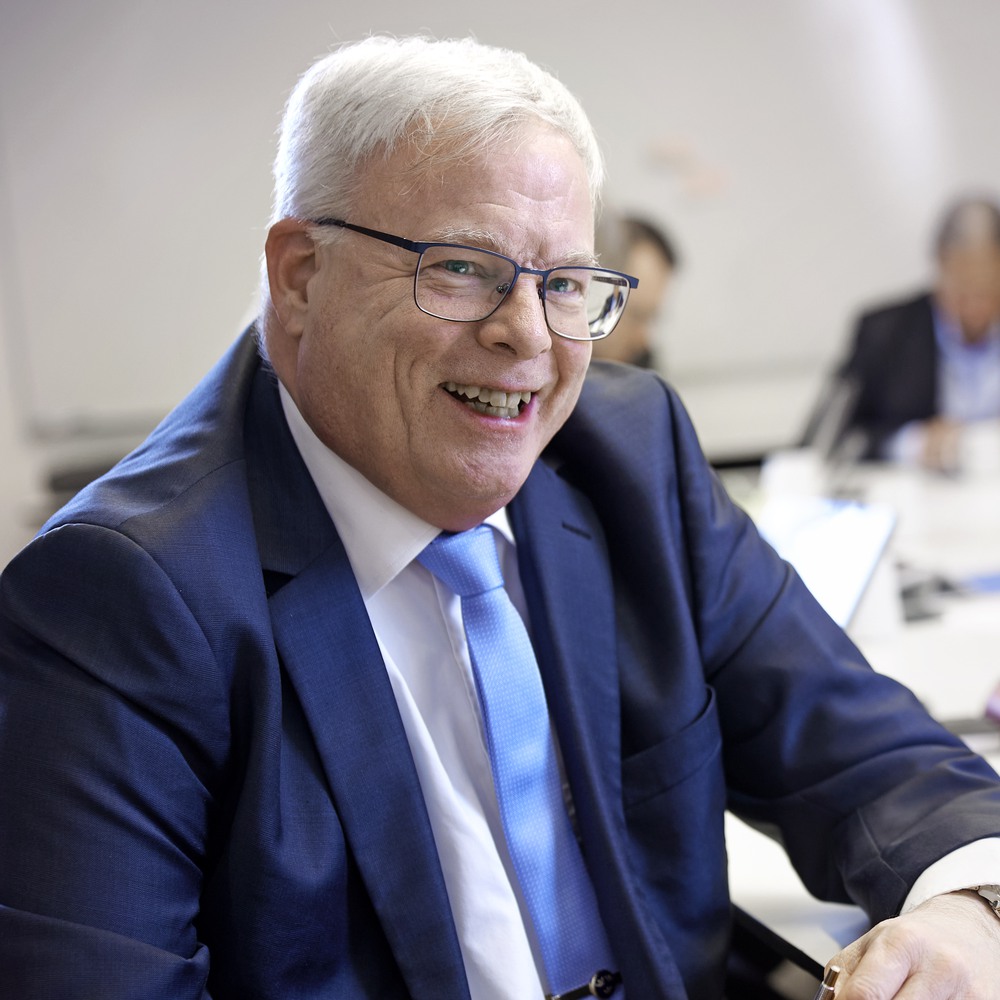 Smiling senior businessman with glasses wearing a blue suit in an office setting