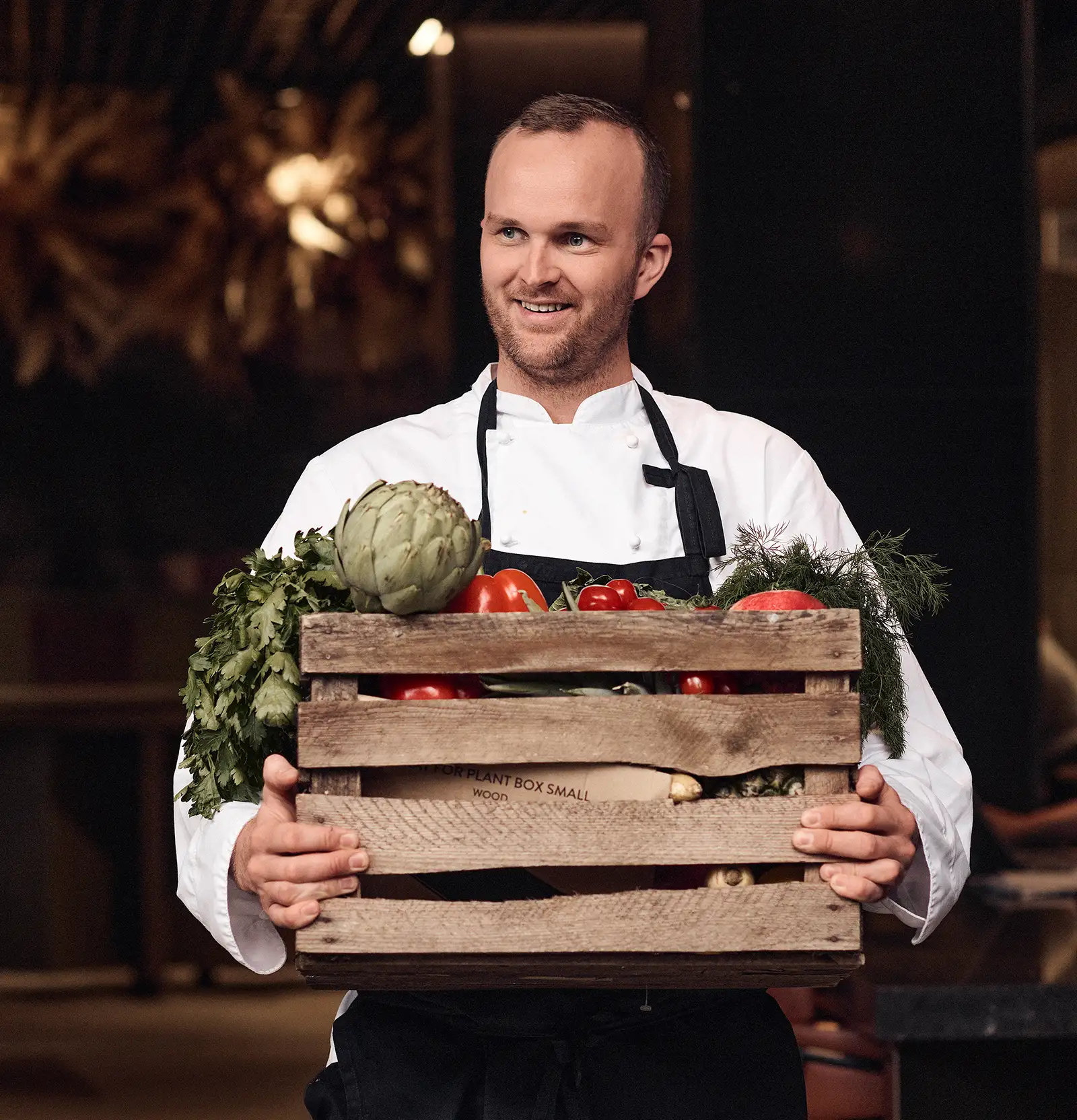 Chef carrying a basked filled with vegetables