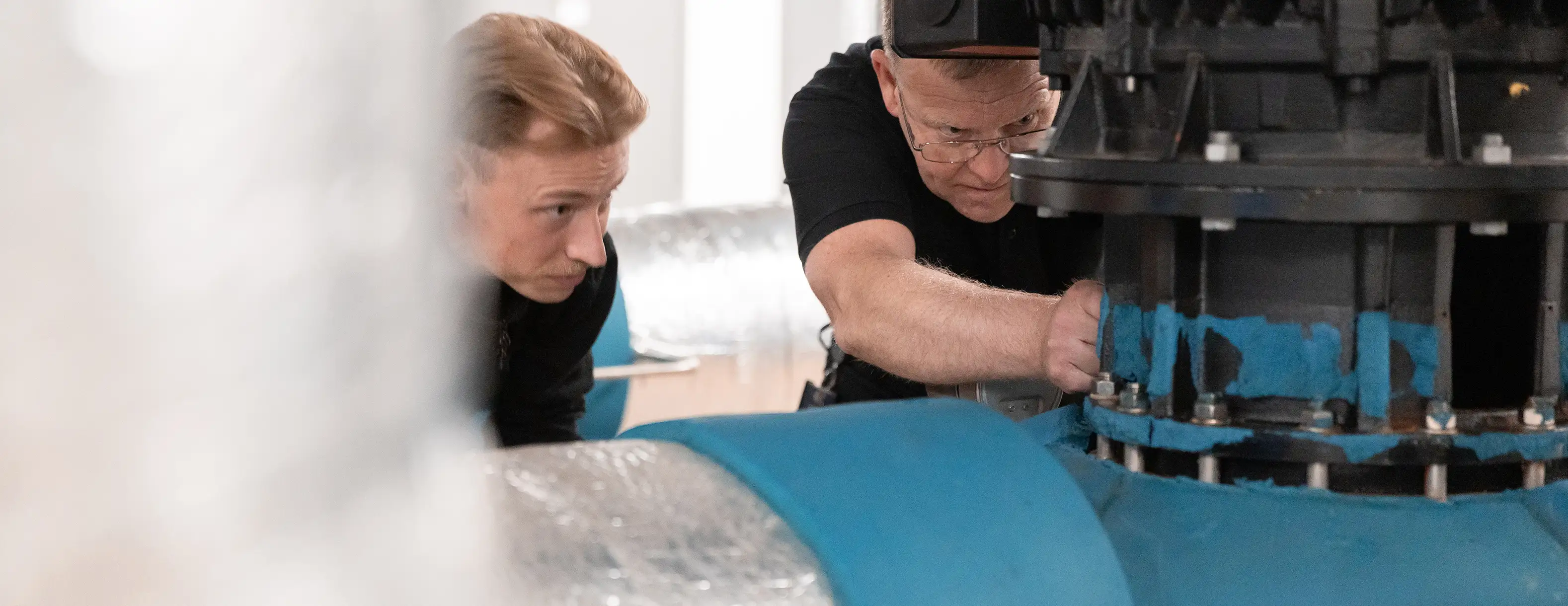 Two property technicians maintaining a large machine in an industrial site