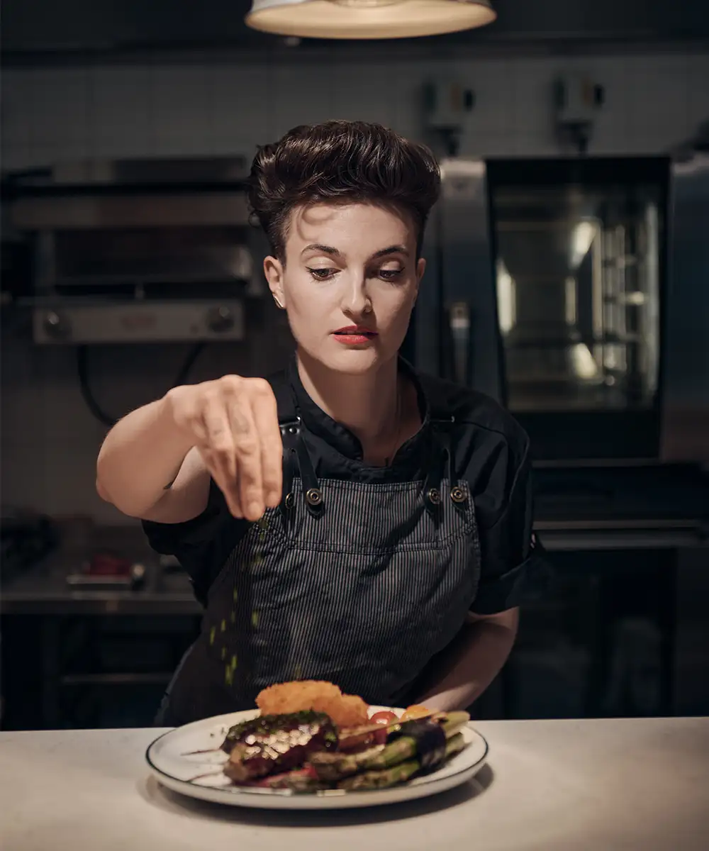 Chef seasoning food on a plate just before serving