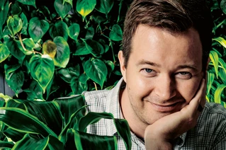Man smiling among green plants.