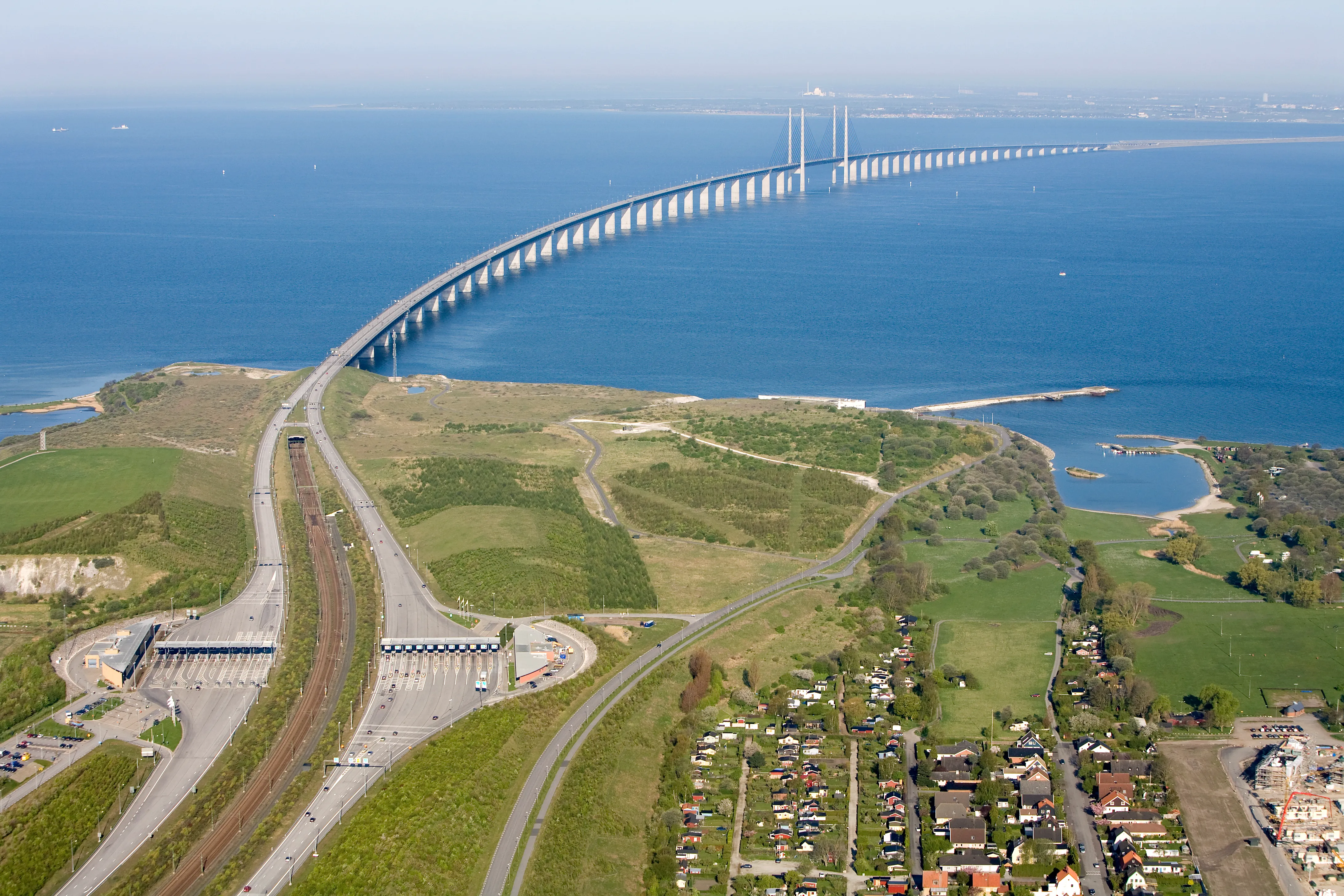 Aerial view of the Oresund Bridge connecting coastal areas over a tranquil sea with clear skies.