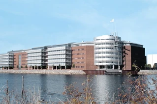 Modern waterfront office buildings with reflective glass windows under a clear blue sky