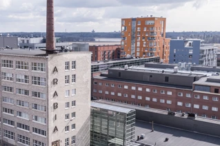Urban landscape featuring the historic Arabia factory chimney in Helsinki with modern buildings in the background.
