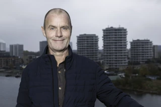 Man in blue jacket in front of city skyline.