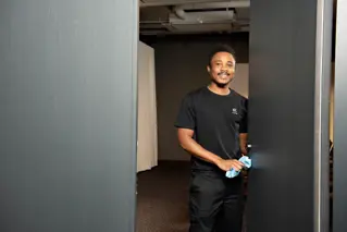 Cleaner standing in a door opening wiping off a door knob