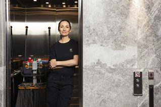 Cleaner with trolley in elevator.